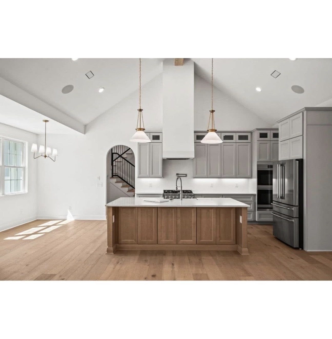 Kitchen in a vaulted great room with grey perimeter cabinets and a stained wood island.